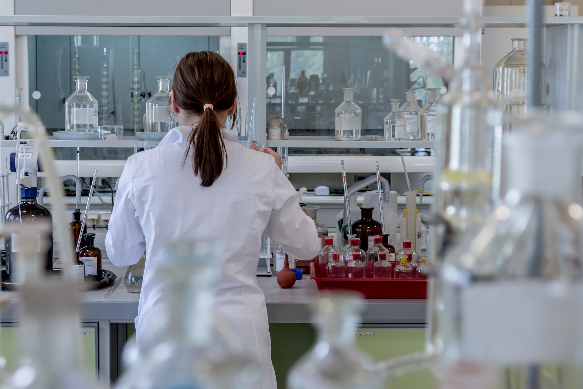 Mujer realizando realizando experimentos de biología en un laboratorio lleno de productos químicos
